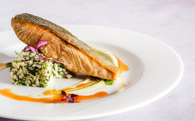 Seared freshwater fish fillet with herb salad on a white plate
