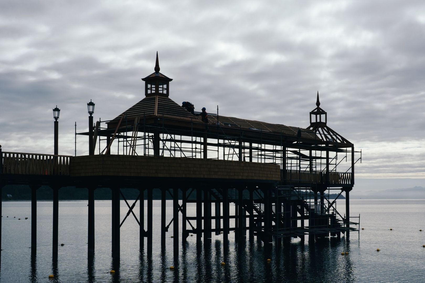 Historic waterside pavilion undergoing roof renovation over a lake