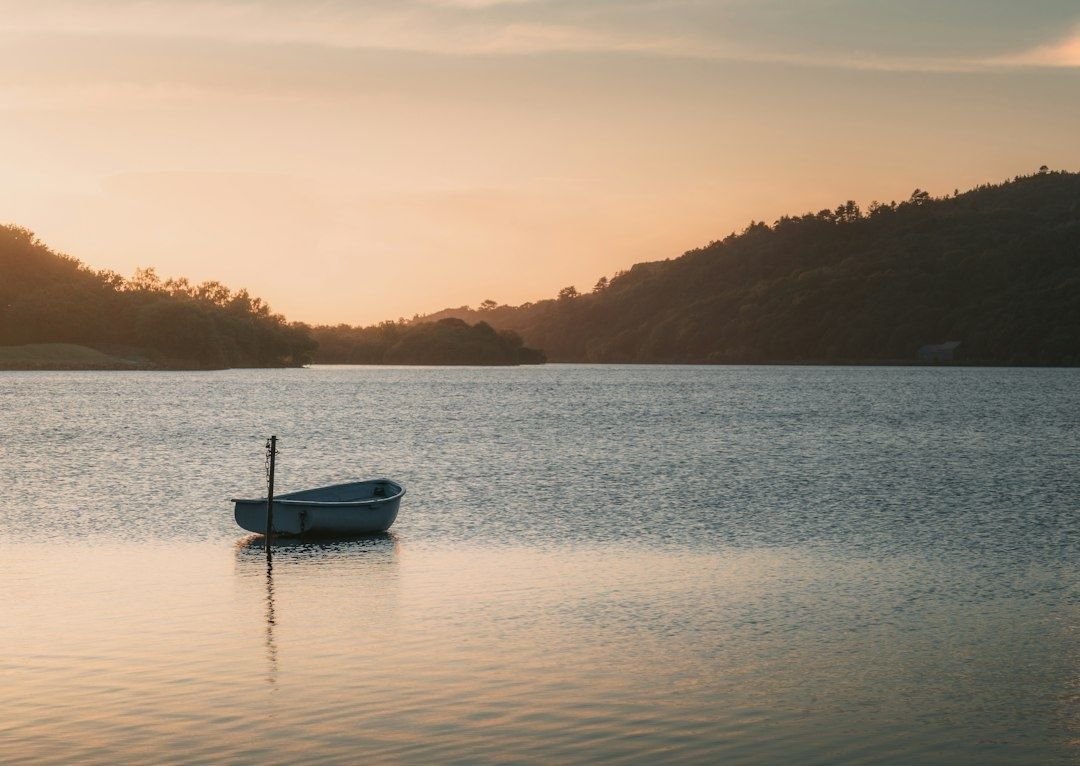 Small fishing boat floating on a calm lake at sunset